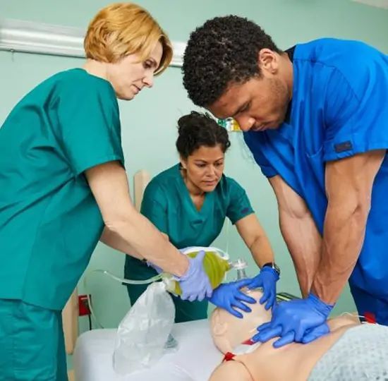 Medical staff practicing CPR on a mannequin in a training room.