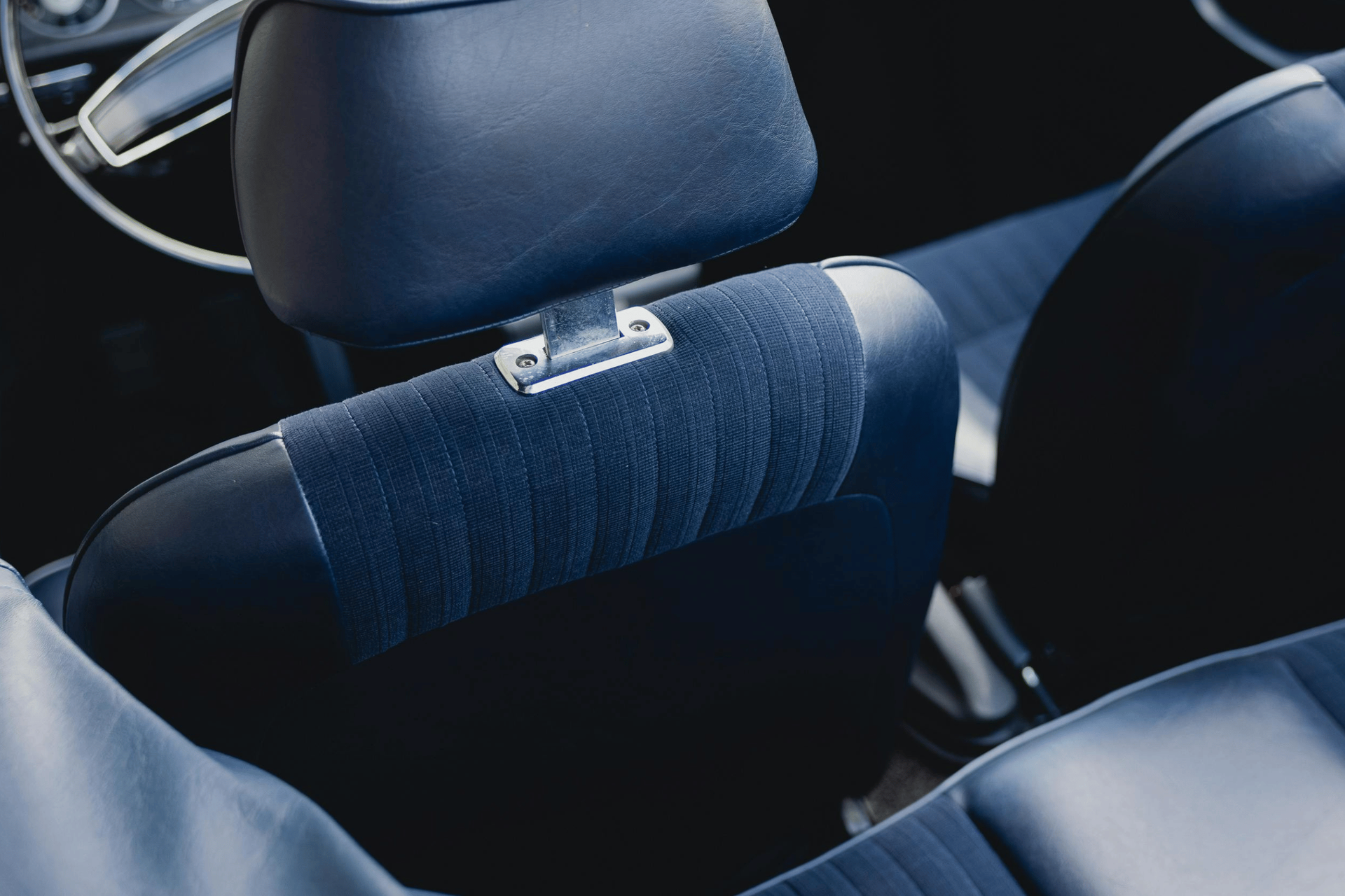Blue headrest on a car seat with a small attached clip, inside a vehicle interior