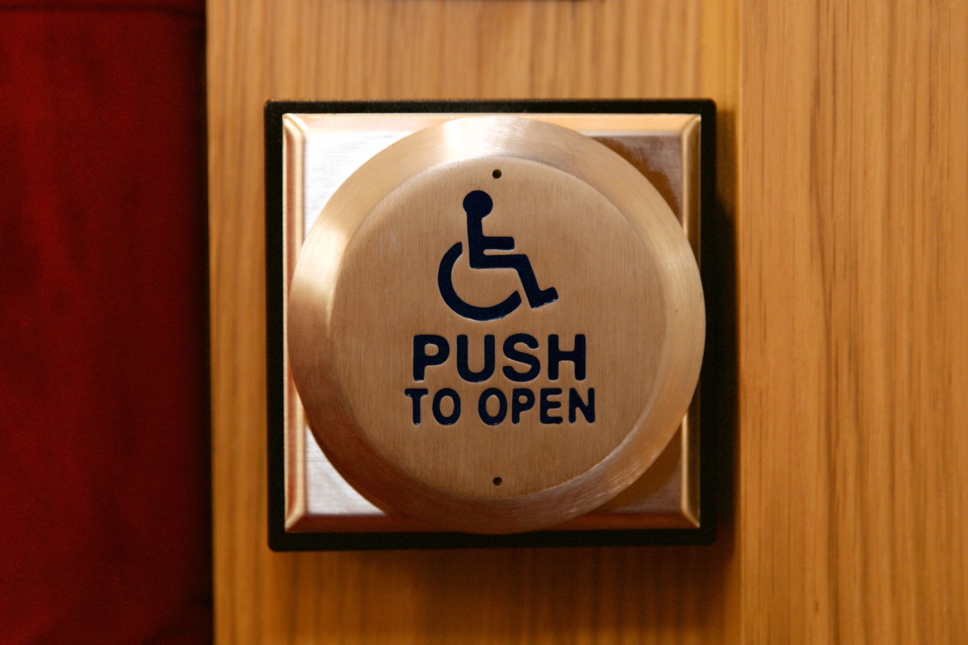 A push to open button with a handicap symbol on it A push to open button with a handicap symbol on it