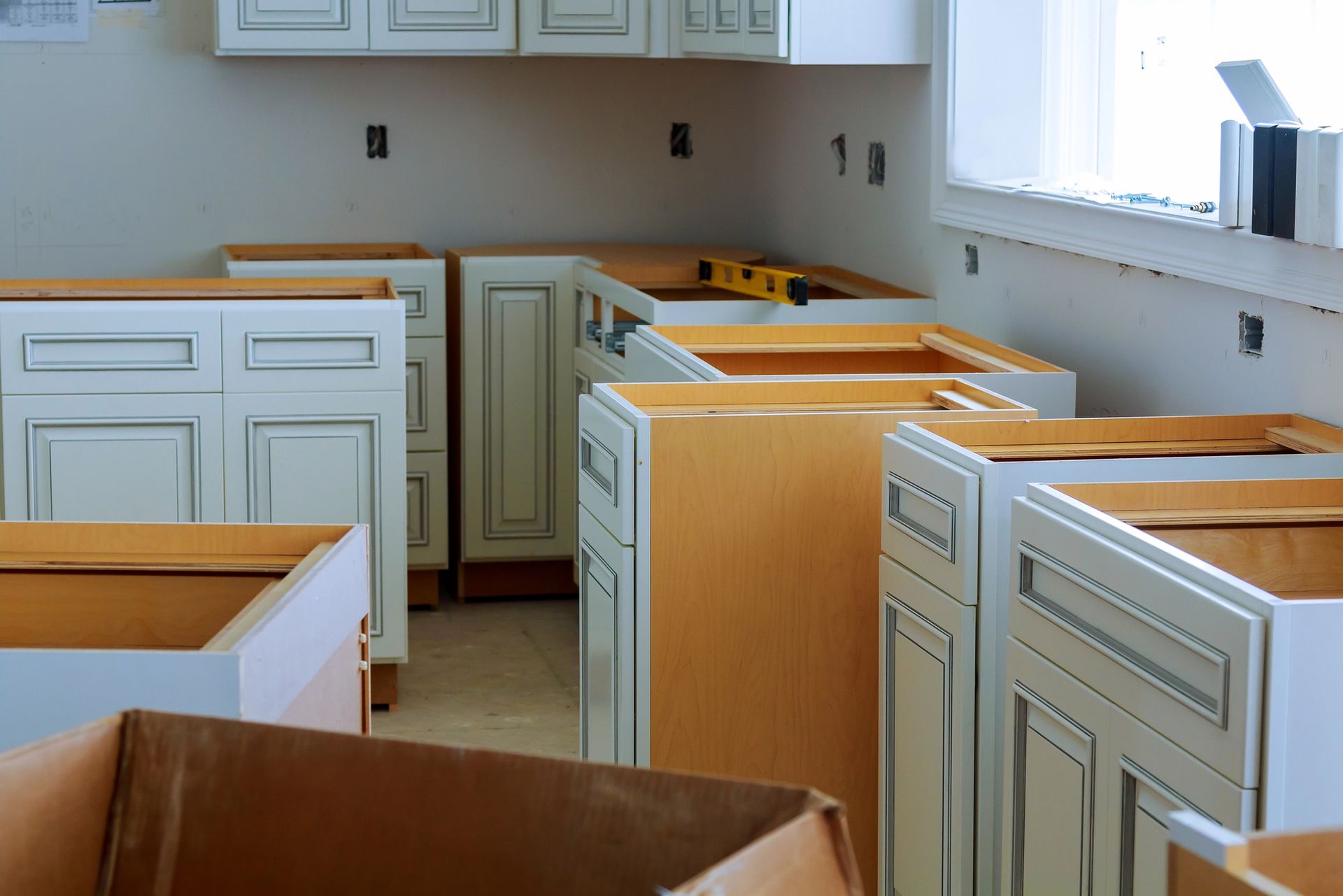 Mobili da cucina in diverse fasi di installazione, con livella e scatole aperte.