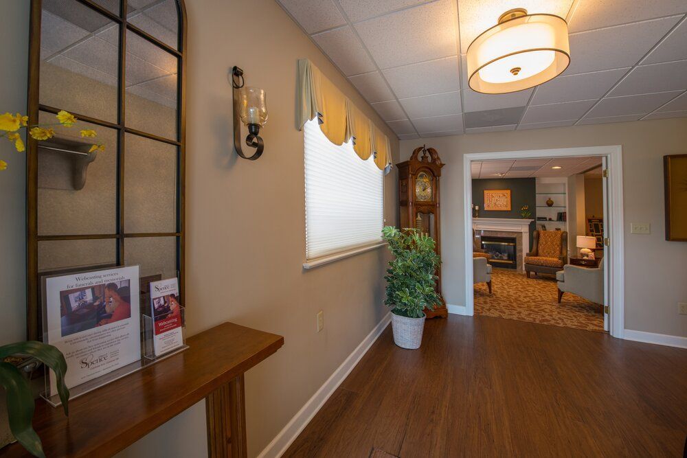 Hallway with wood floor, pendant light, potted plant, window, and doorway to a living room