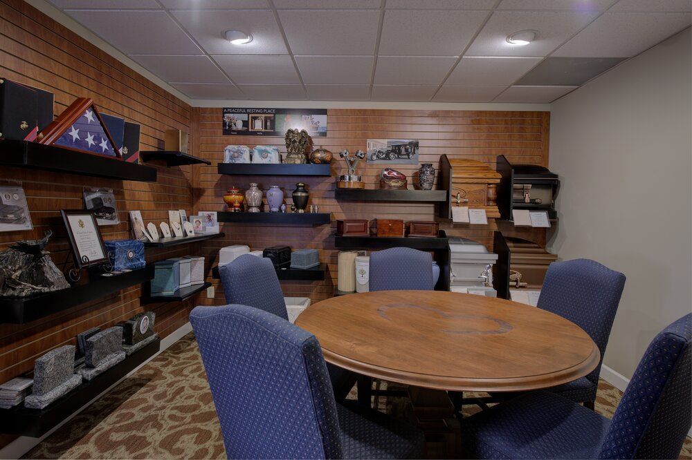 Small office meeting room with round wooden table, blue chairs, shelves, and brick walls