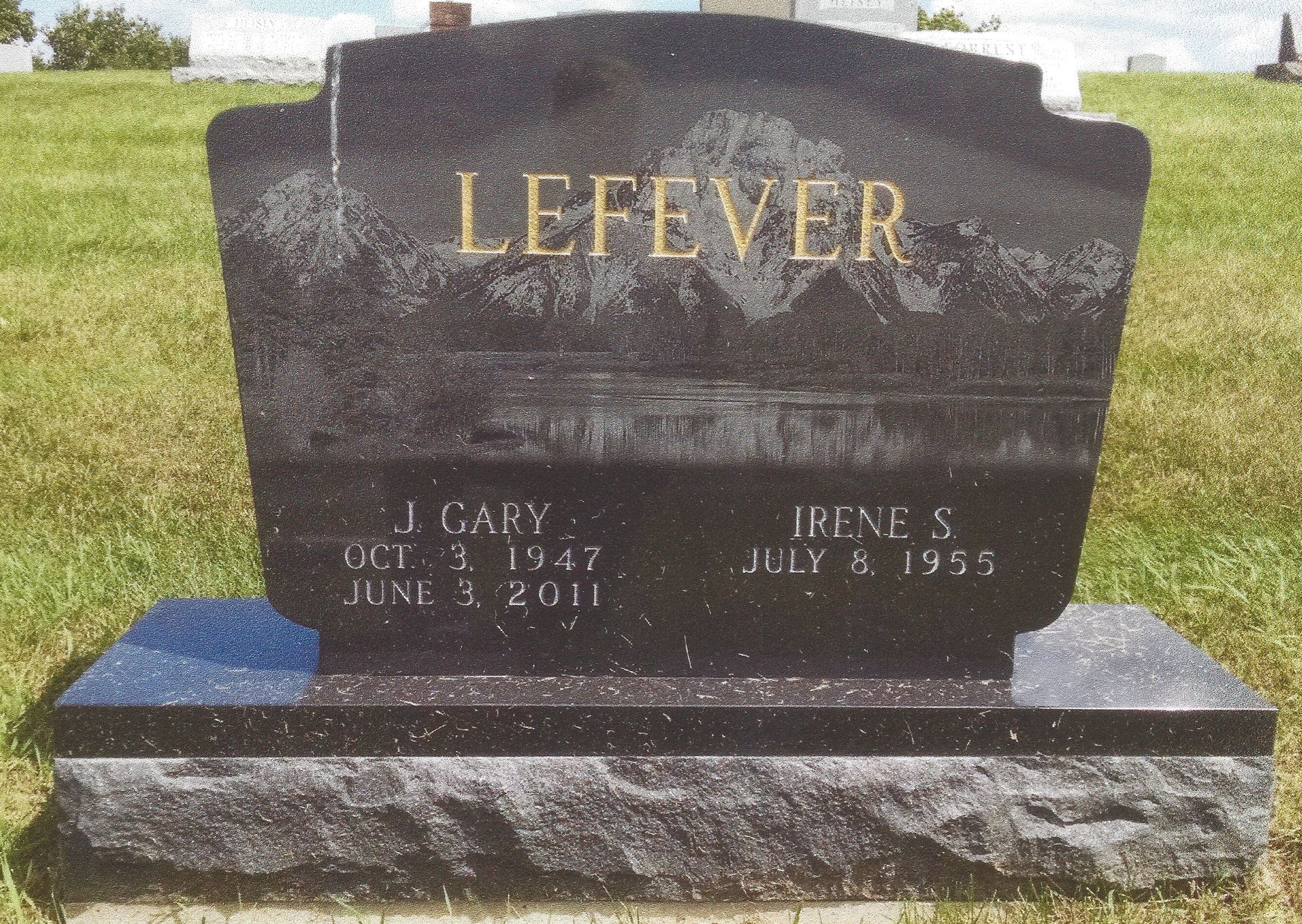 Lefever family gravestone in a grassy cemetery, dark stone with gold lettering.