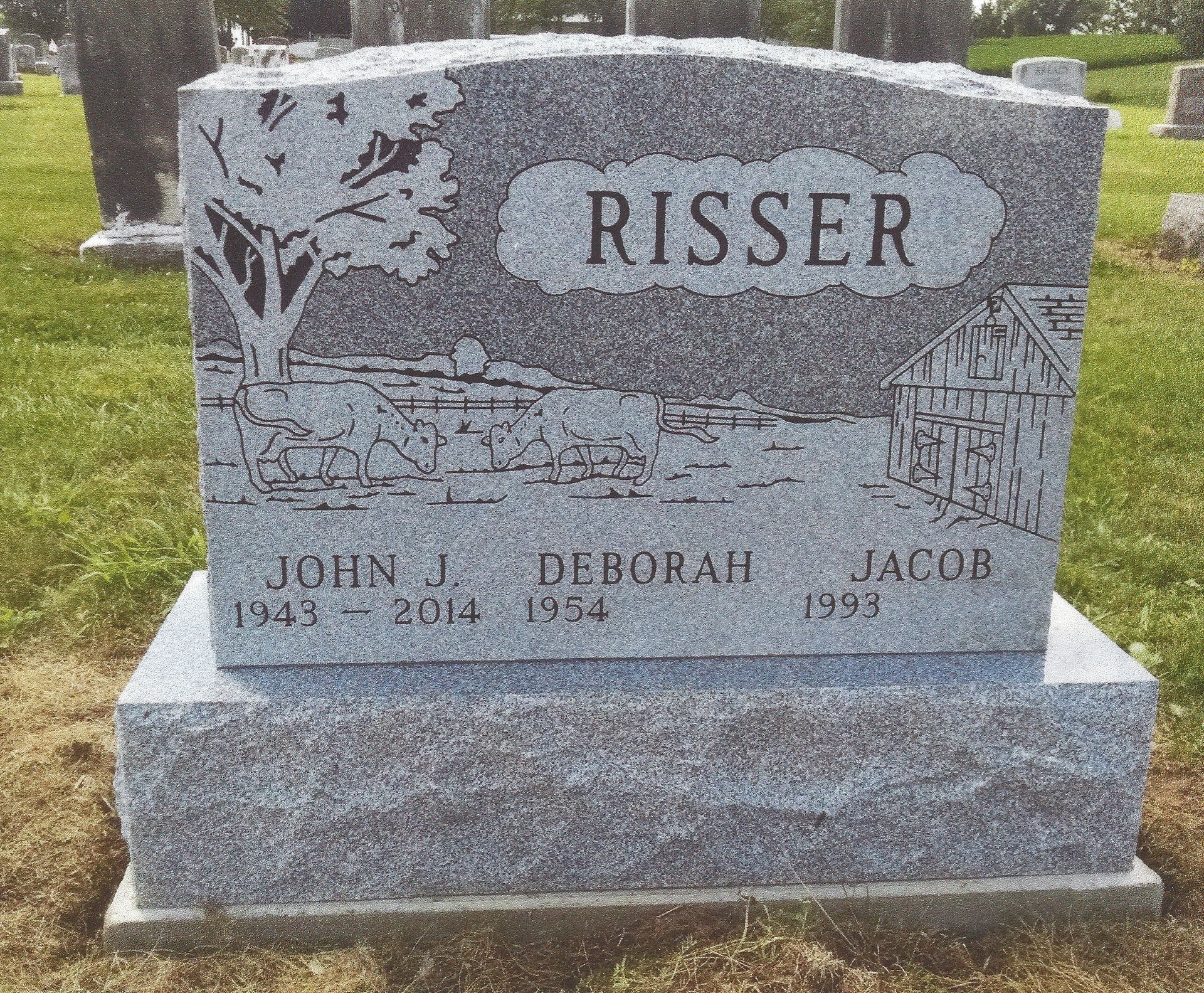 Gray granite gravestone in a grassy cemetery, engraved “RISSER” with three names below.