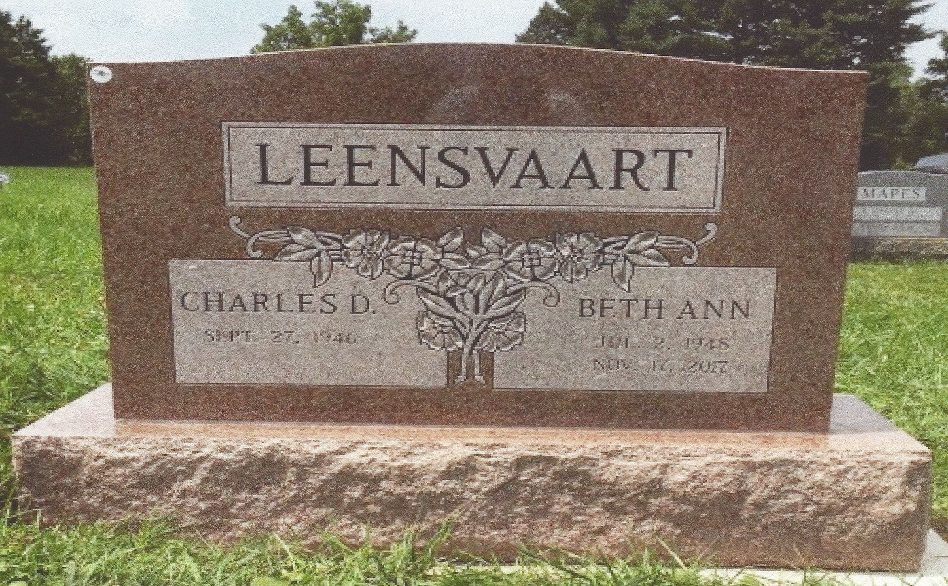 Leensvaart stone monument sign with engraved names and a tree design in front of a grassy outdoor area
