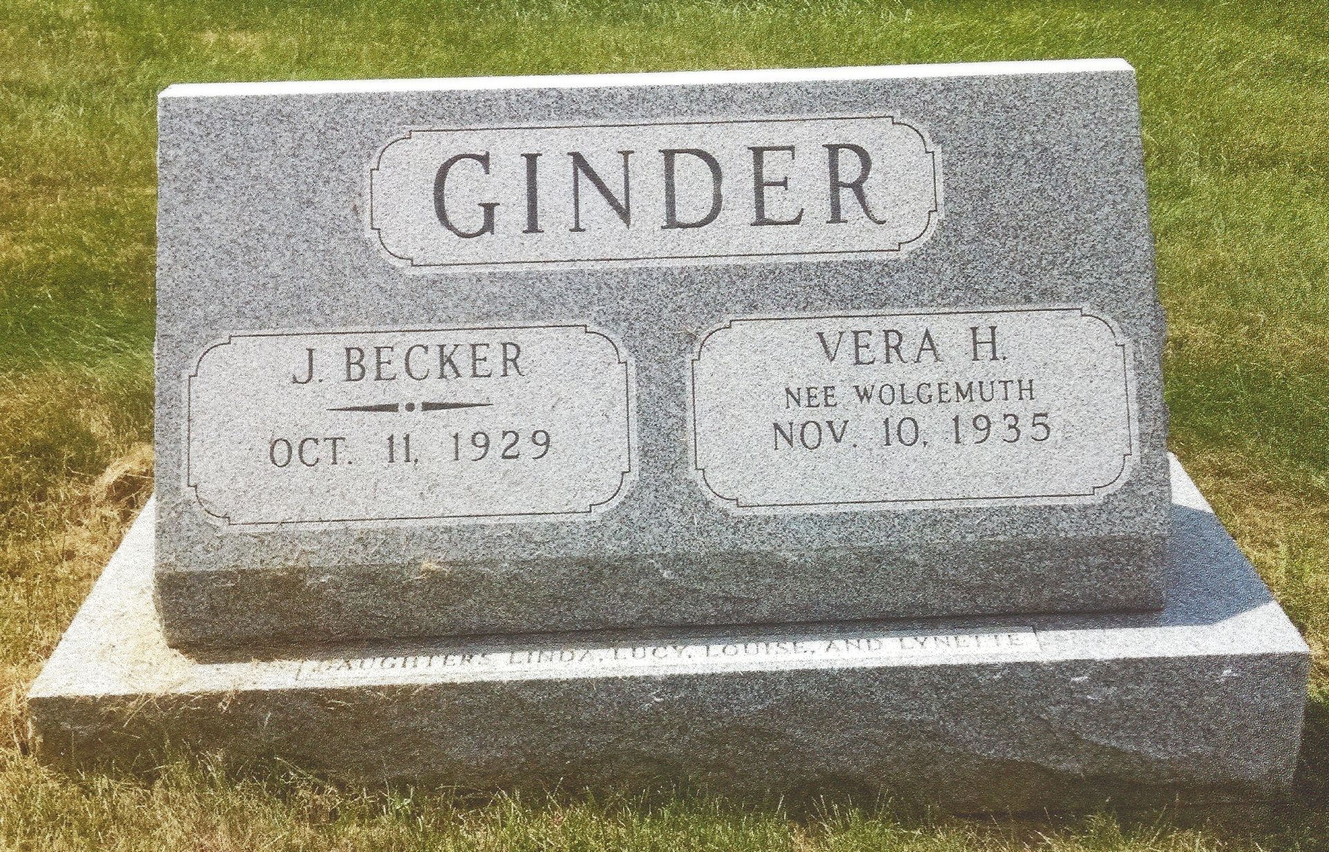Gray Ginder family gravestone in a grassy cemetery, with two smaller plaques at the base
