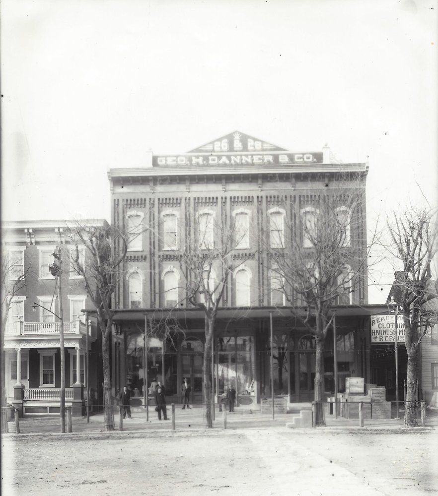 Historic black-and-white street photo of the George Danner & Co. storefront with arched windows and bare trees