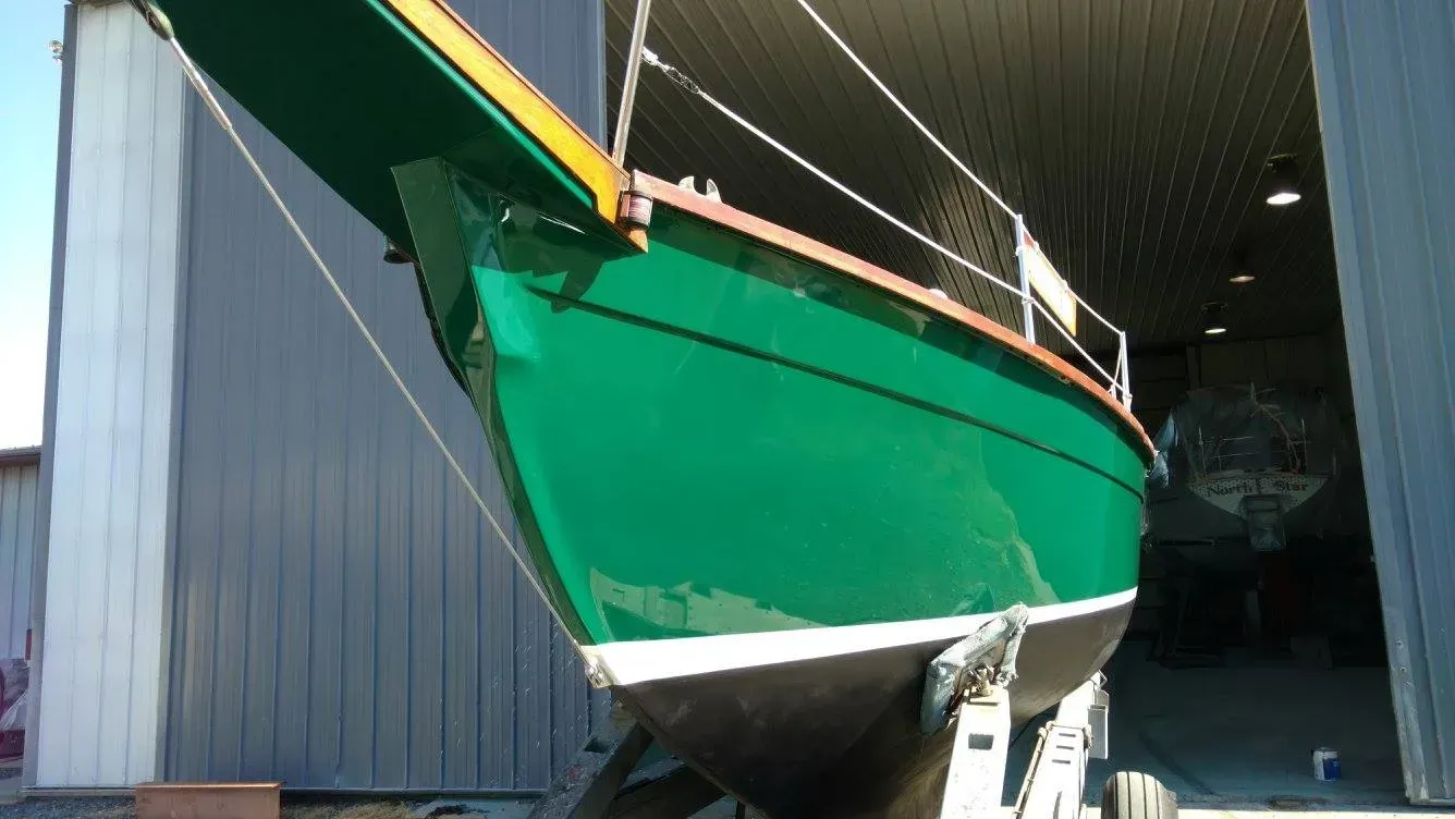 A green boat is parked in front of a building