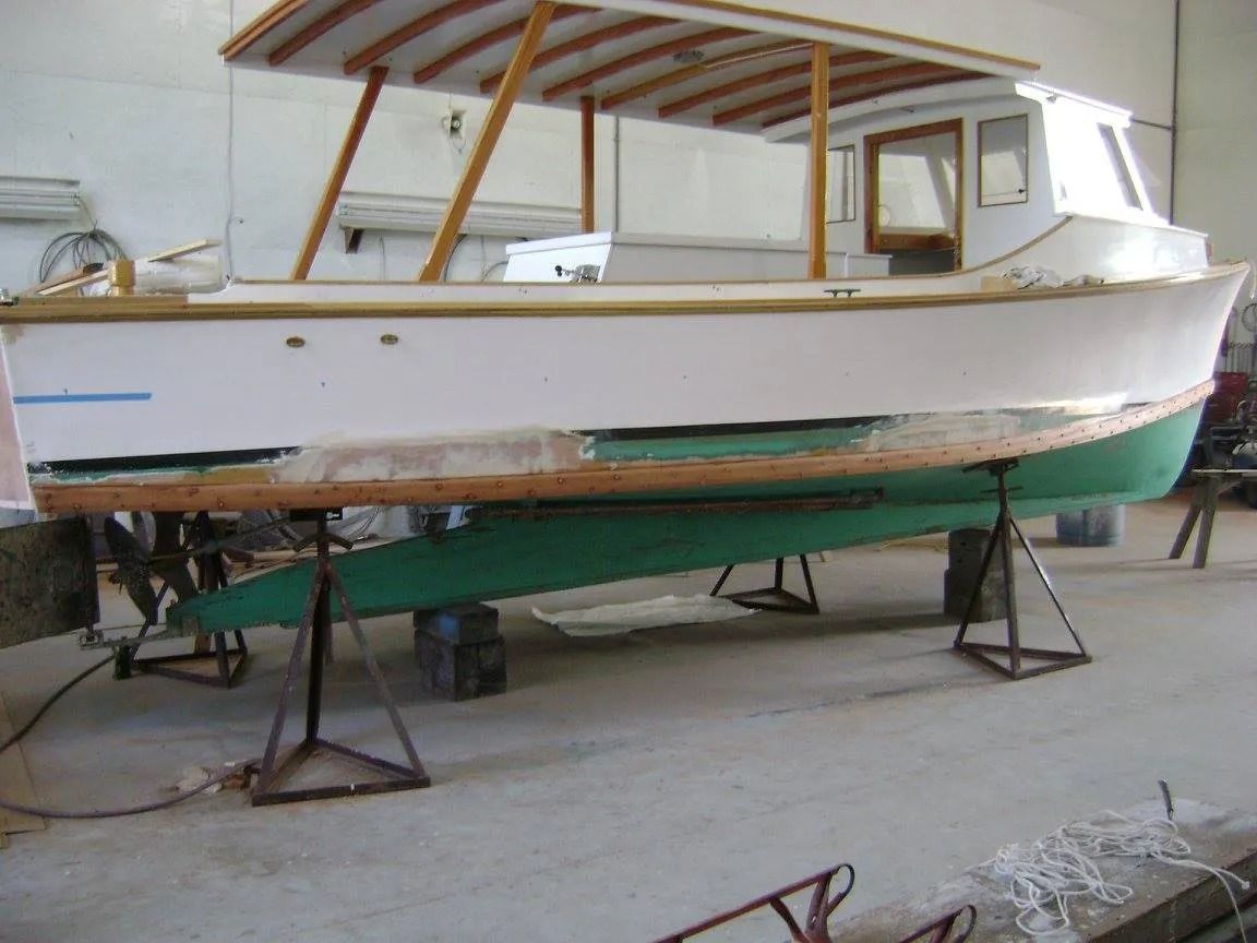 A white and green boat is sitting on a concrete floor