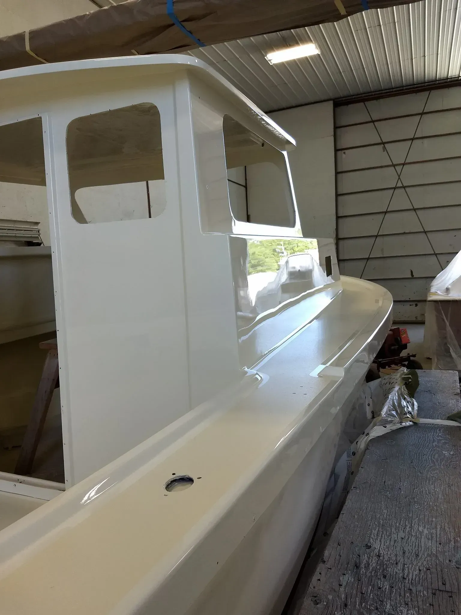 A white boat is being built in a warehouse.