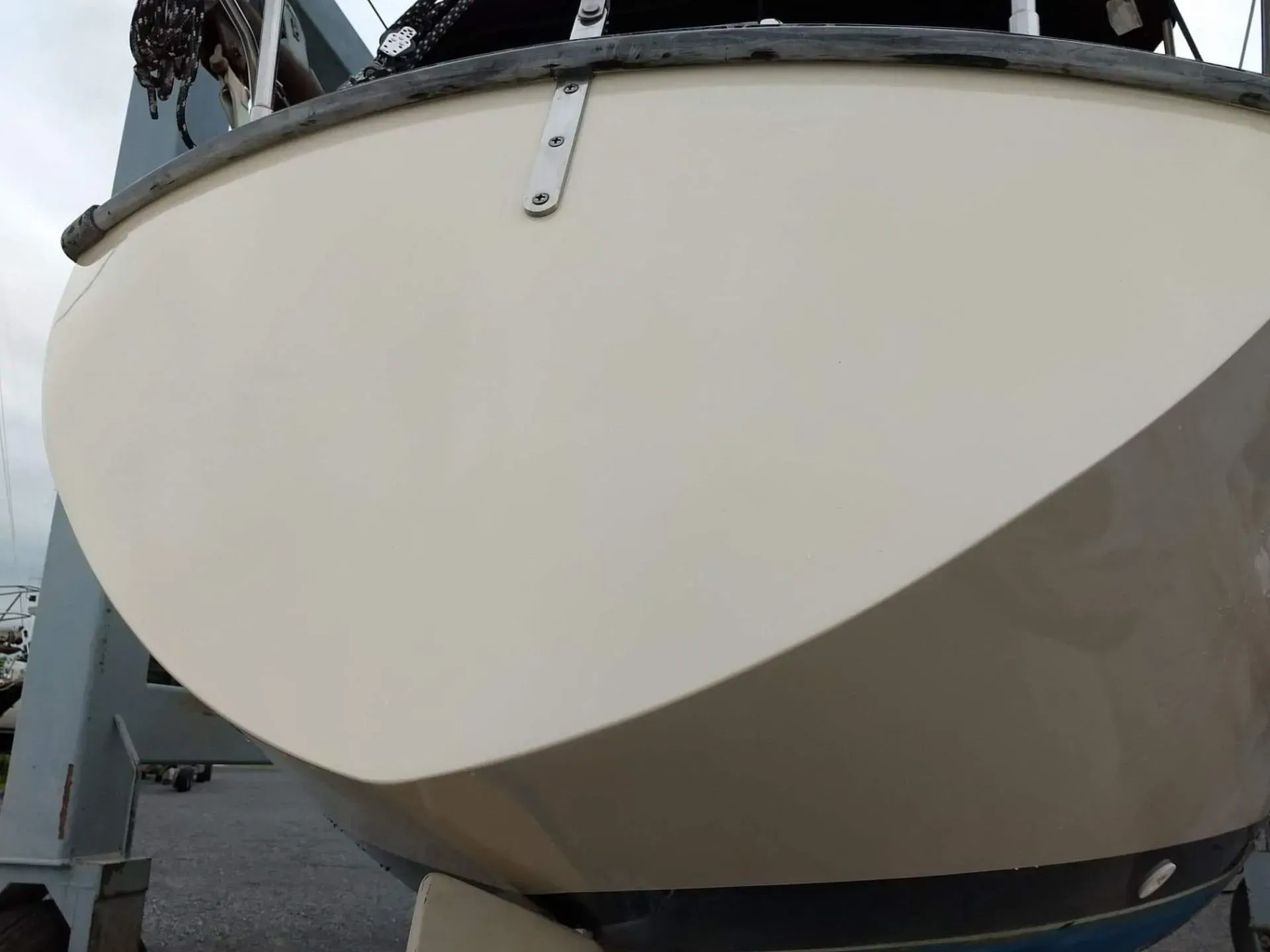 A white boat with a black sail is sitting on a dock