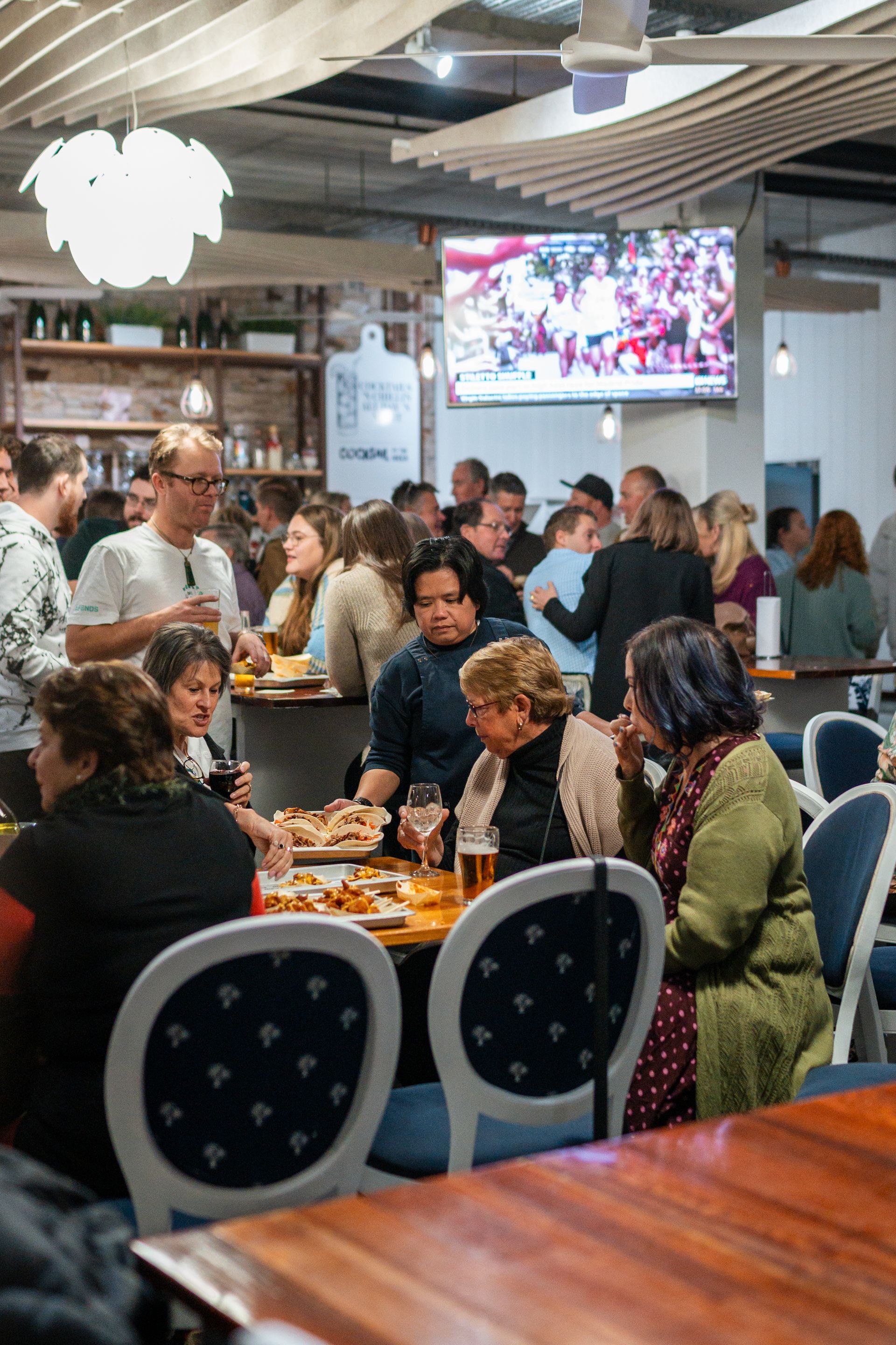 A Group of People Are Sitting at Tables in A Restaurant — Chop 'n Chill in Port Macquarie, NSW
