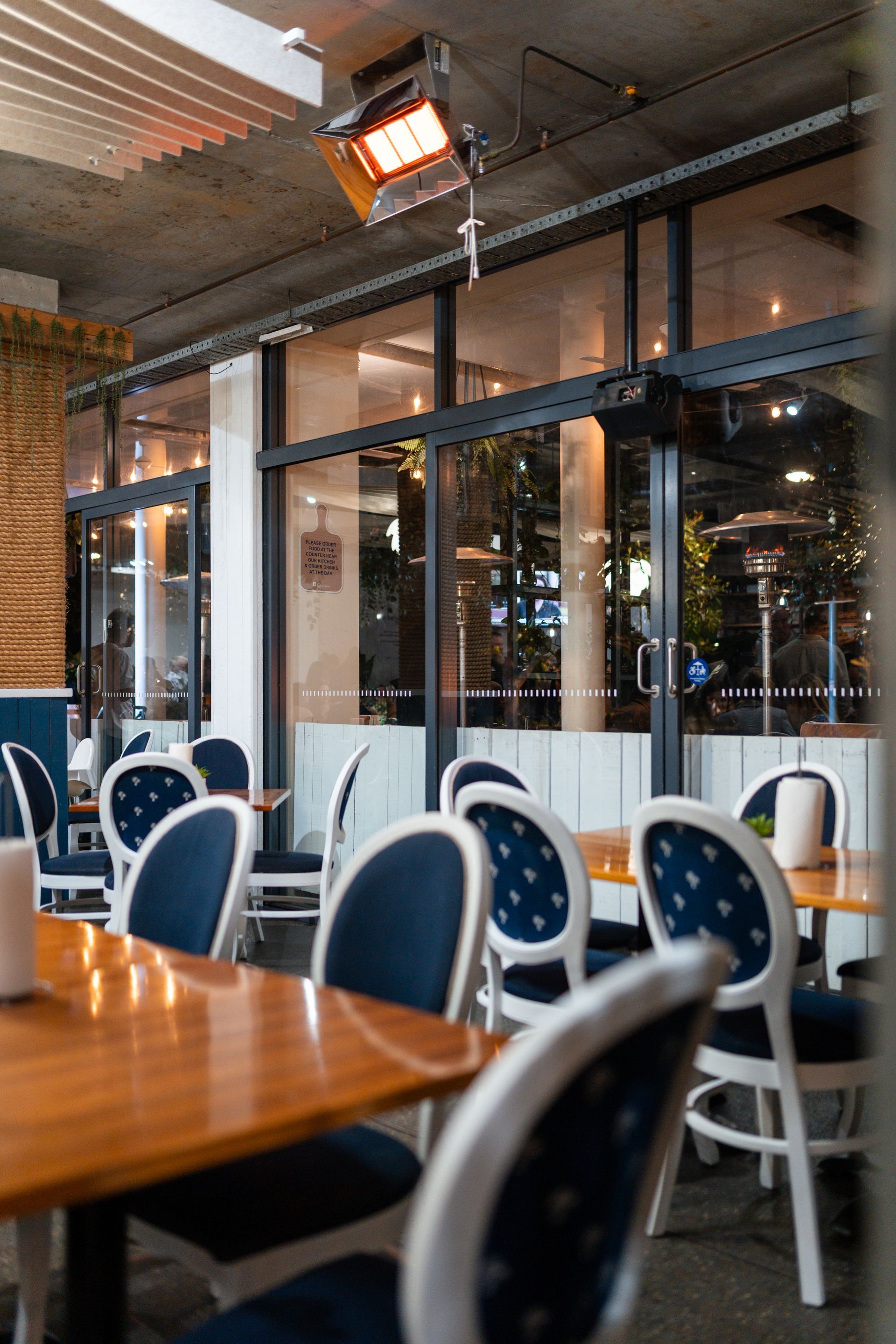 A Restaurant with Tables and Chairs and A Heater Hanging from The Ceiling — Chop 'n Chill in Port Macquarie, NSW