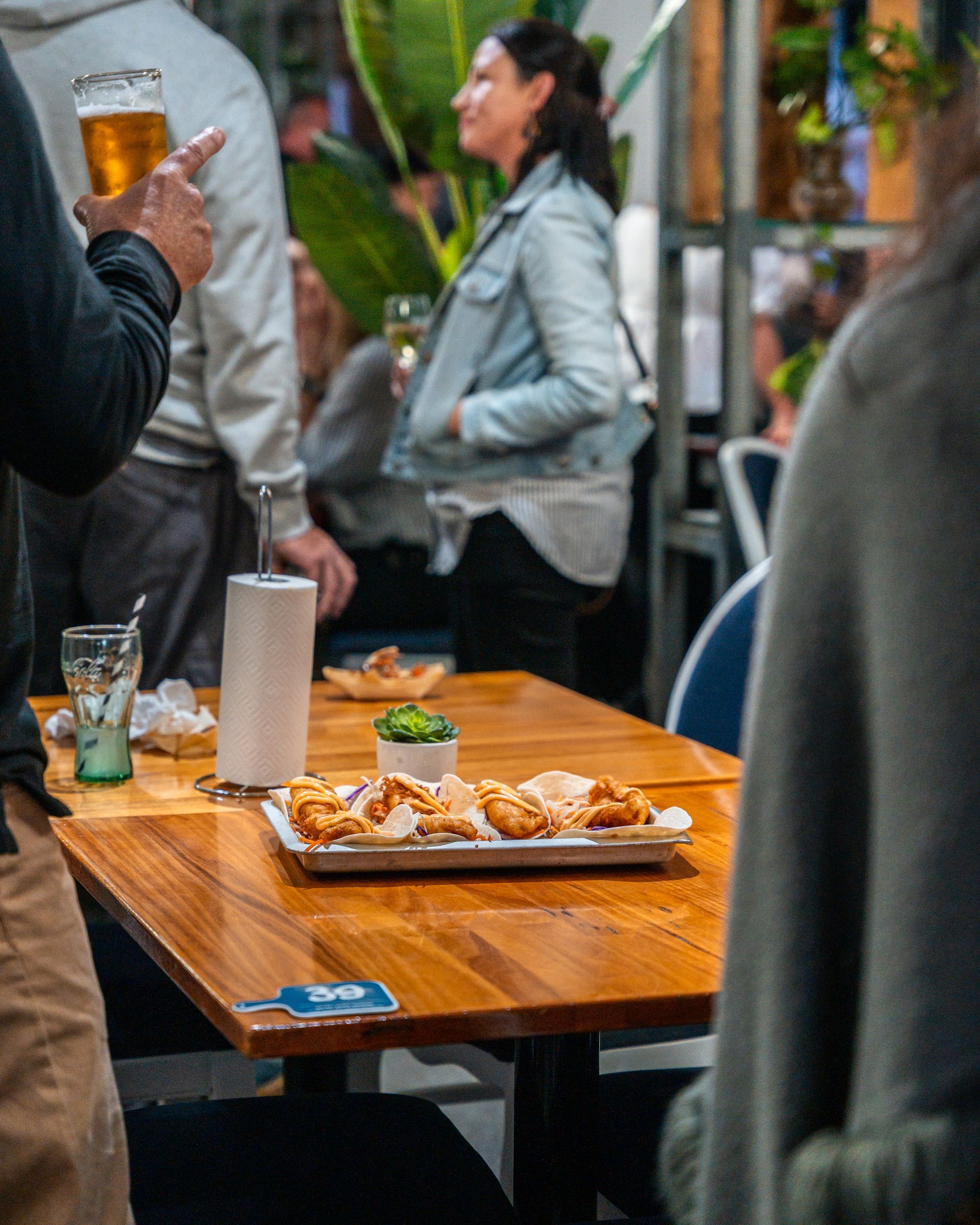 A Group of People Are Sitting at A Table with Food and Drinks — Chop 'n Chill in Port Macquarie, NSW