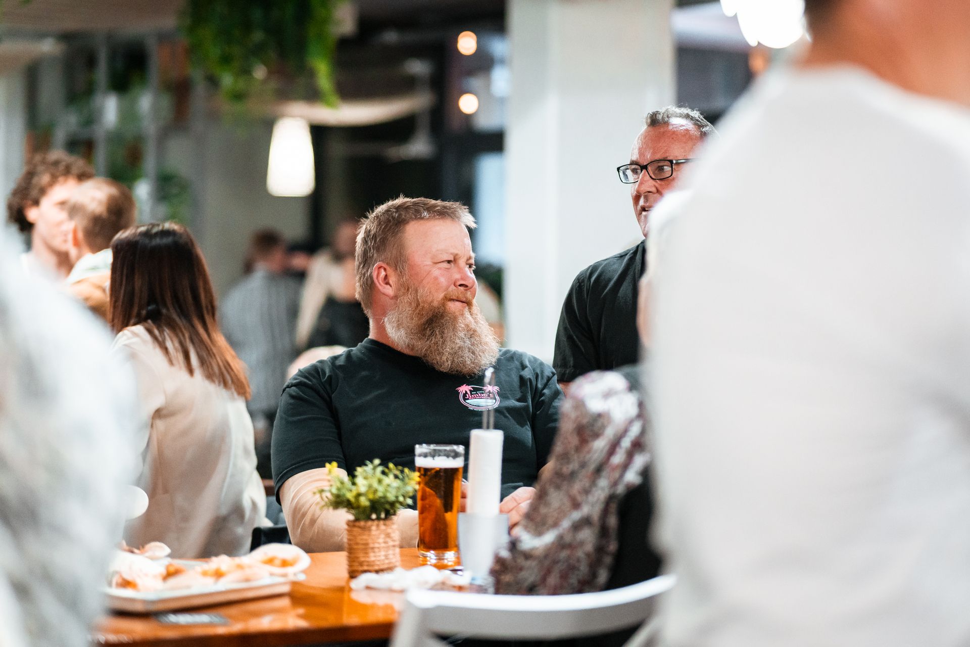 A Man with A Beard Is Sitting at A Table with A Glass of Beer — Chop 'n Chill in Port Macquarie, NSW