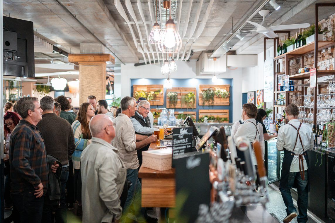 A Group of People Are Standing Around a Bar in A Restaurant — Chop 'n Chill in Port Macquarie, NSW