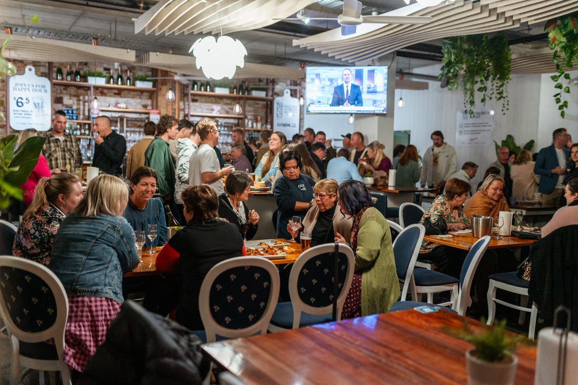 A Large Group of People Are Sitting at Tables in A Restaurant — Chop 'n Chill in Port Macquarie, NSW