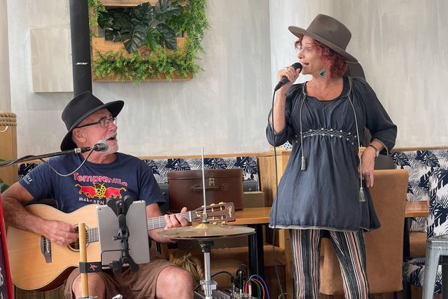 A Man Is Playing a Guitar and A Woman Is Singing Into Microphones — Chop 'n Chill in Port Macquarie, NSW