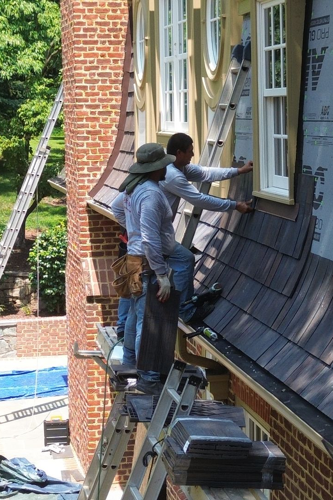 Workers painting the exterior of a brick building on scaffolding and ladders