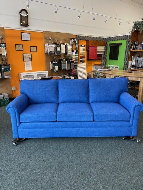 A blue couch in a room with a clock on the wall