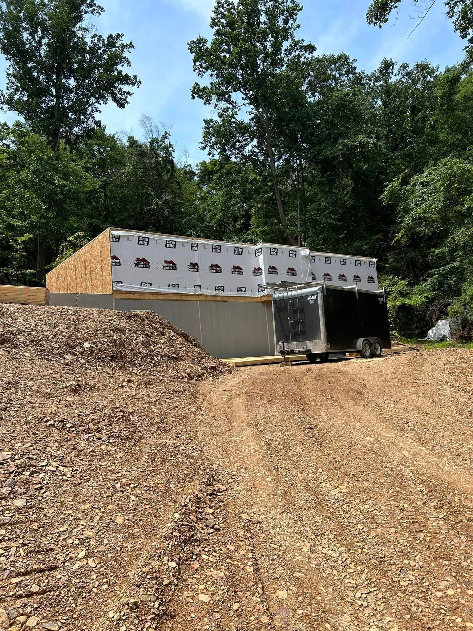 Construction trailer beside large piles of wood chips under trees
