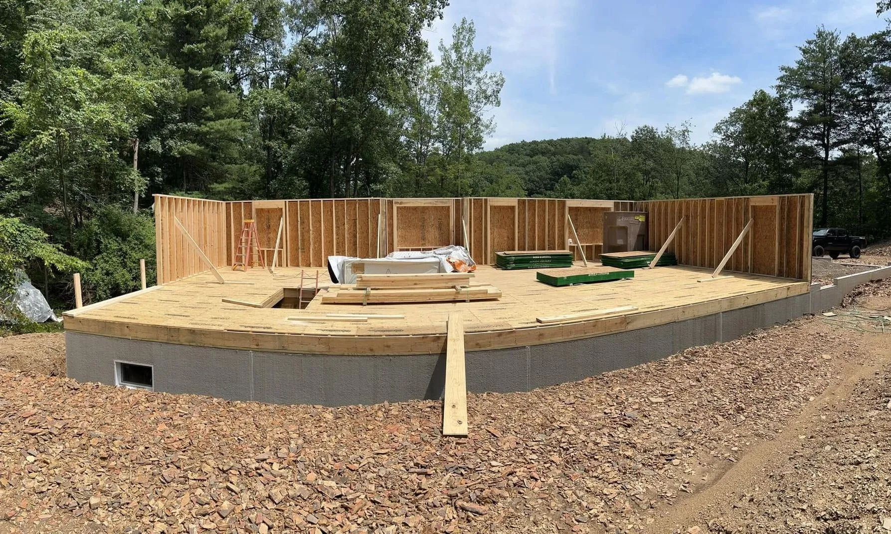 Round foundation under construction with wood framing and gravel surrounding it outdoors