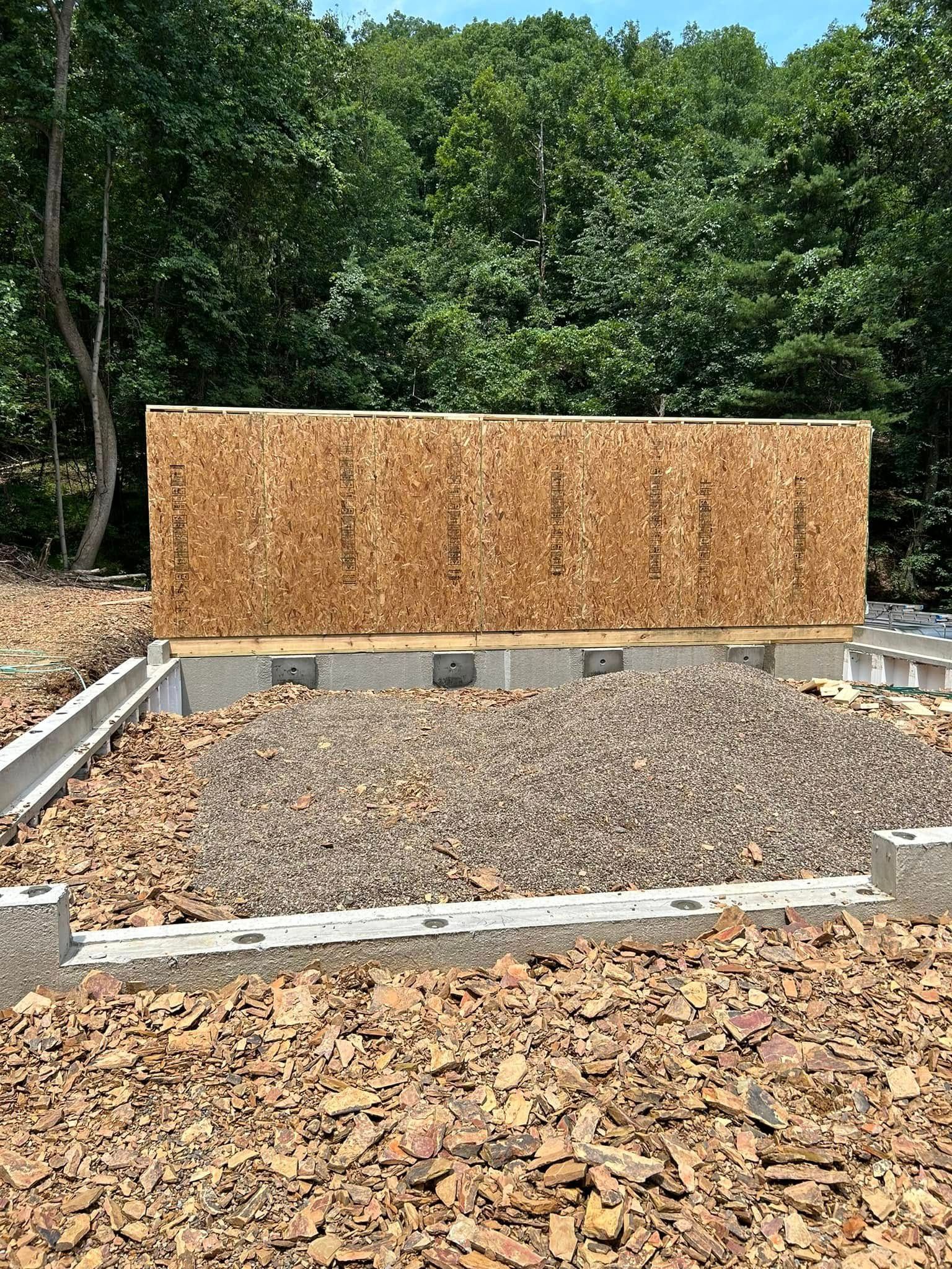 Outdoor gravel area with a wooden privacy screen and concrete edging in a leafy setting