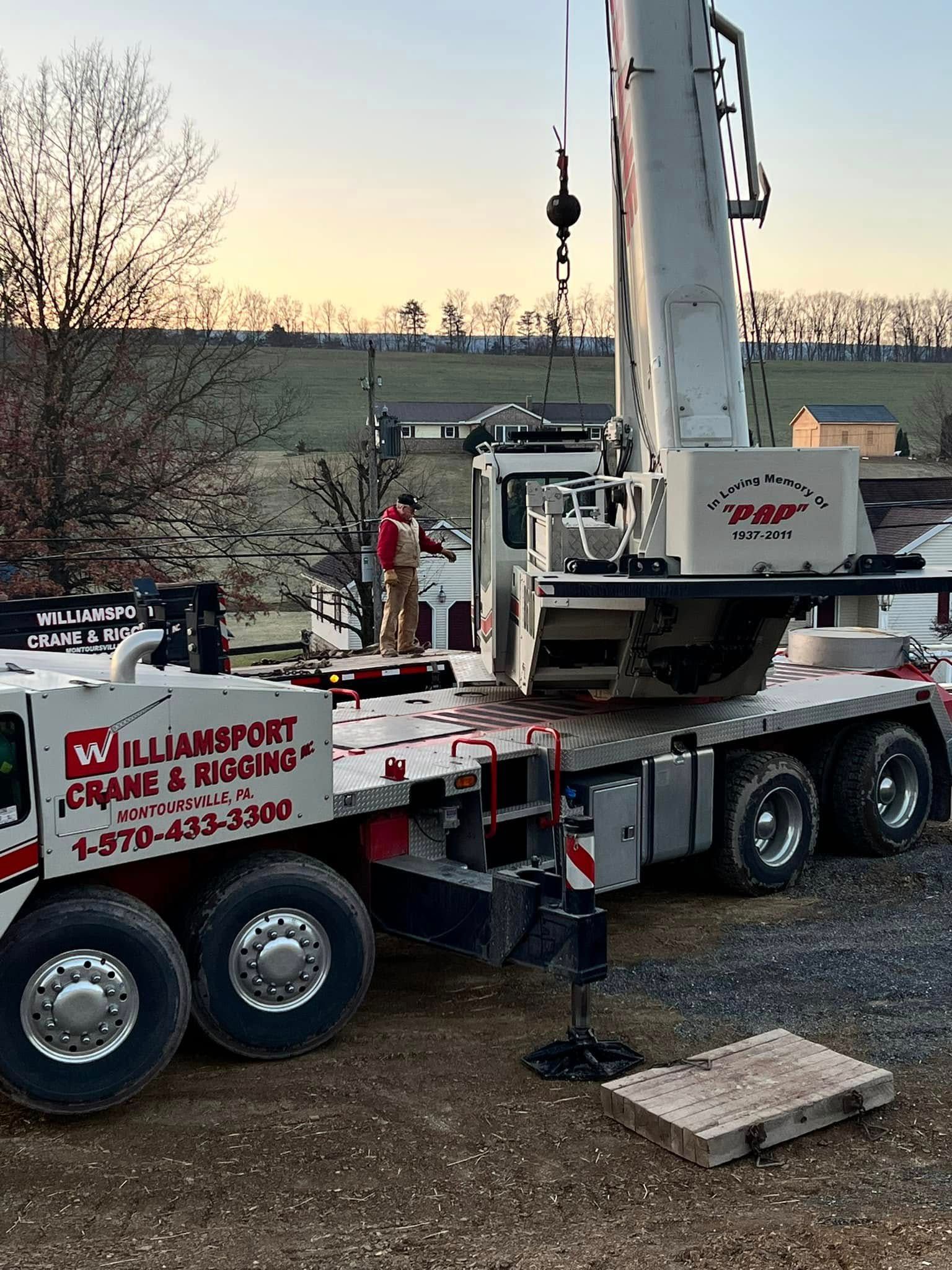 Heavy equipment drill rig on a trailer at a construction site, with a worker and sunset background