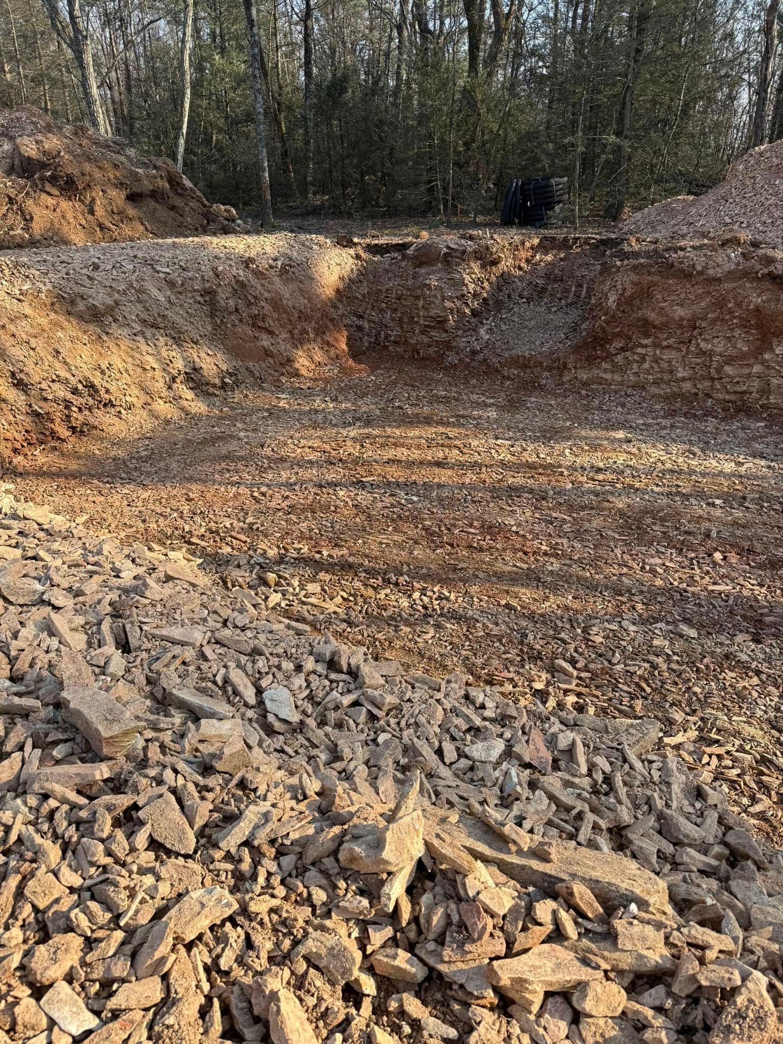 Rocky excavation site with bare dirt and trees in the background