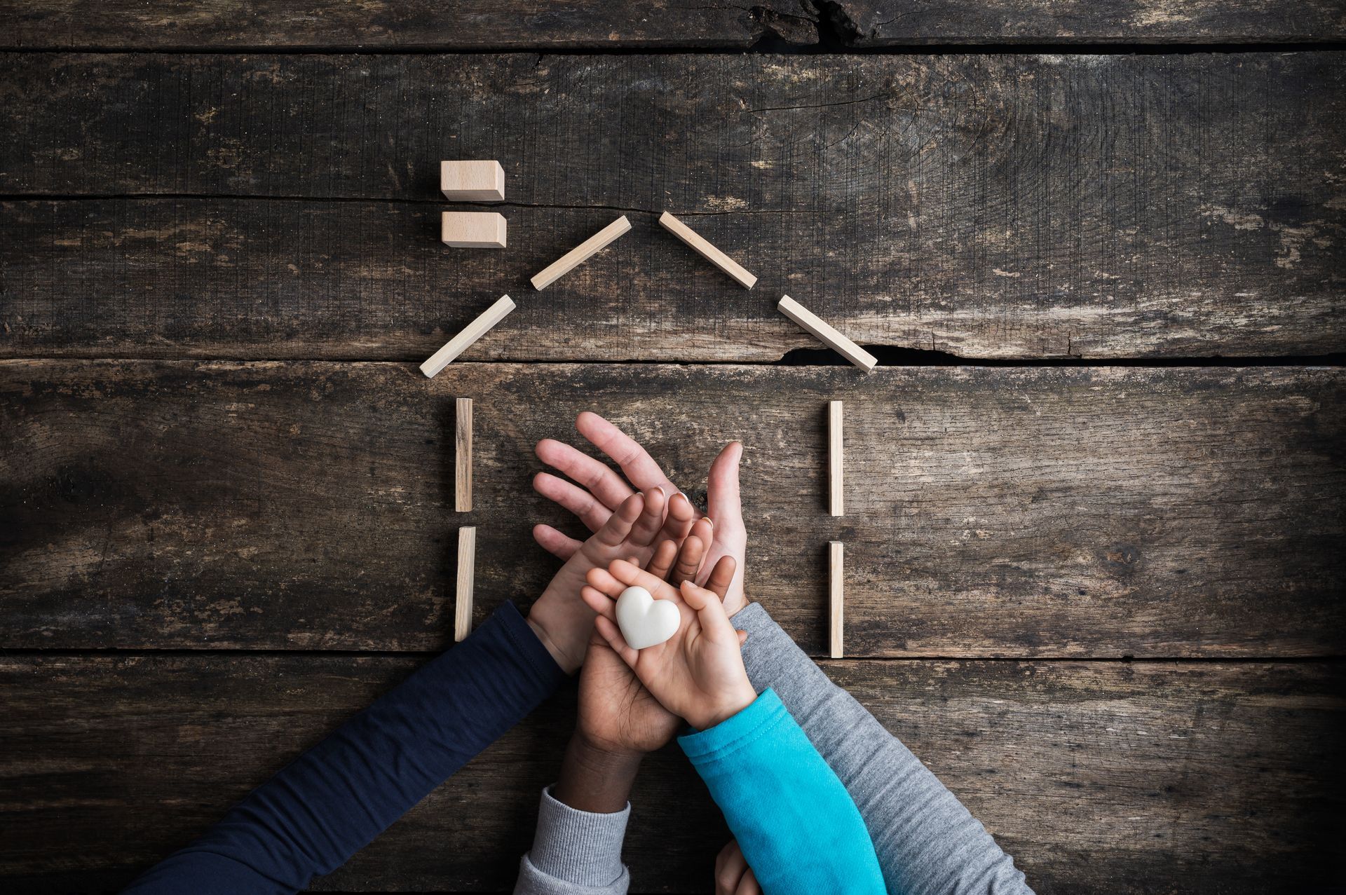 Hands holding a heart inside a house outline symbolizing family care