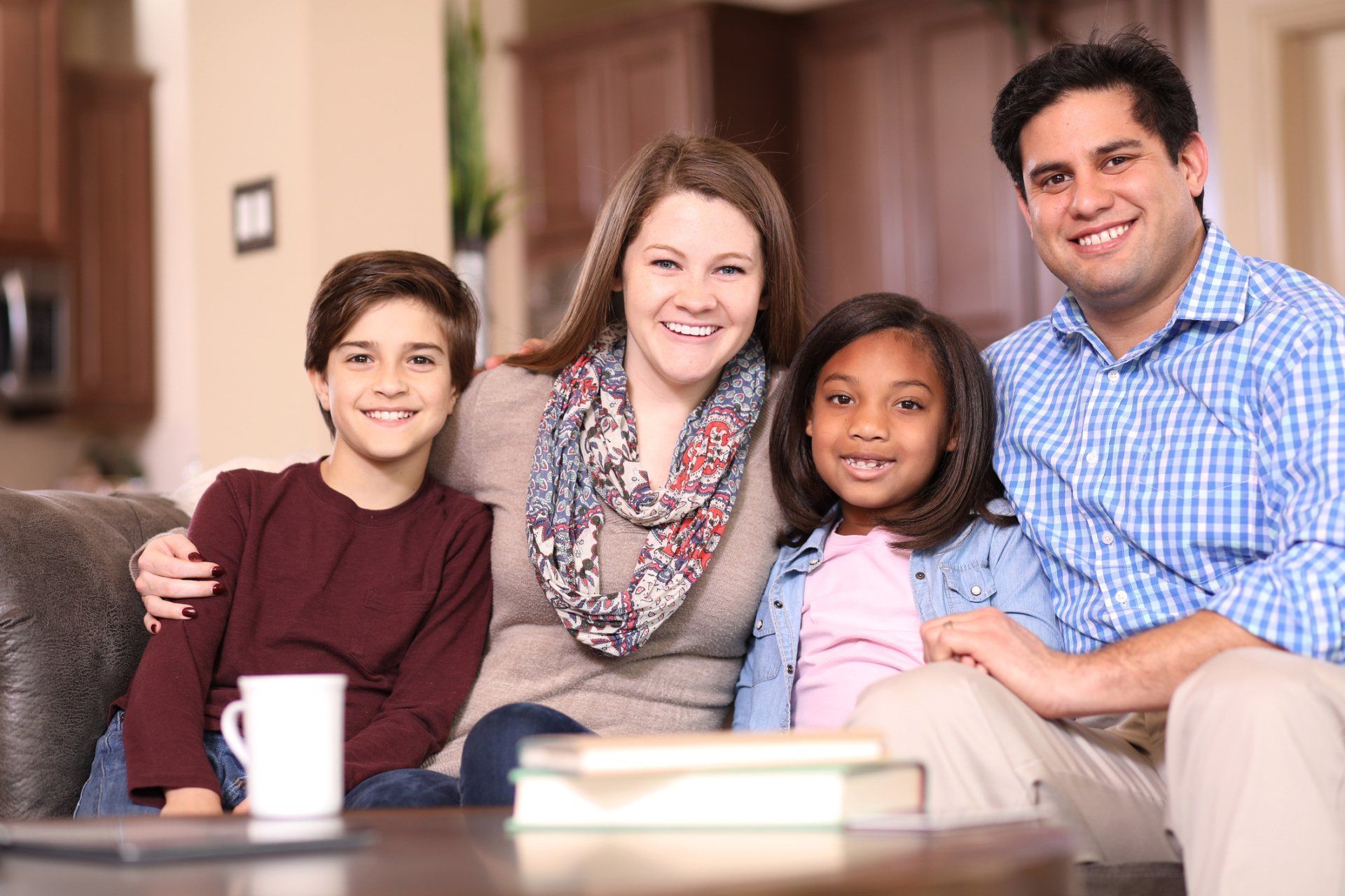 Family of four smiling on a couch in a living room.