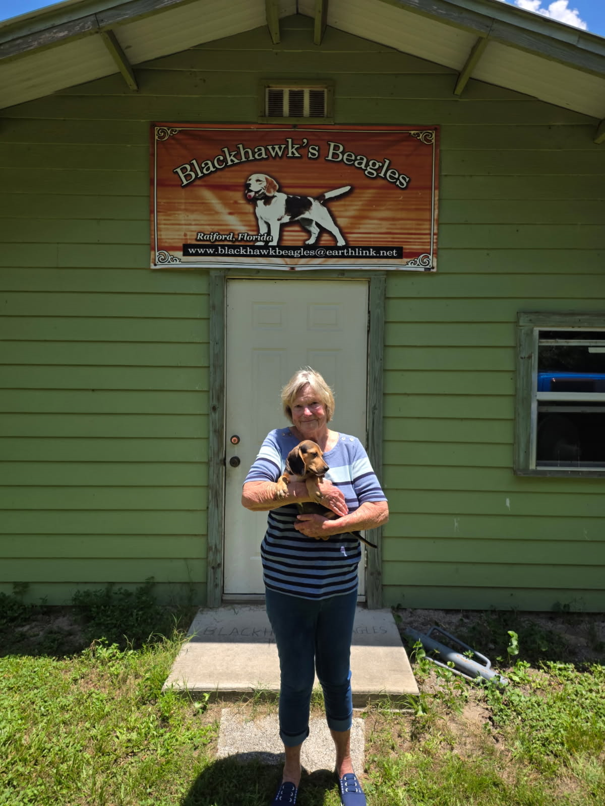 A woman is holding a dog in front of a building.