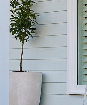 A Potted Plant Is Sitting Next to A Window on The Side of A House — Bootle Timber QLD Pty Ltd in Garbutt, QLD