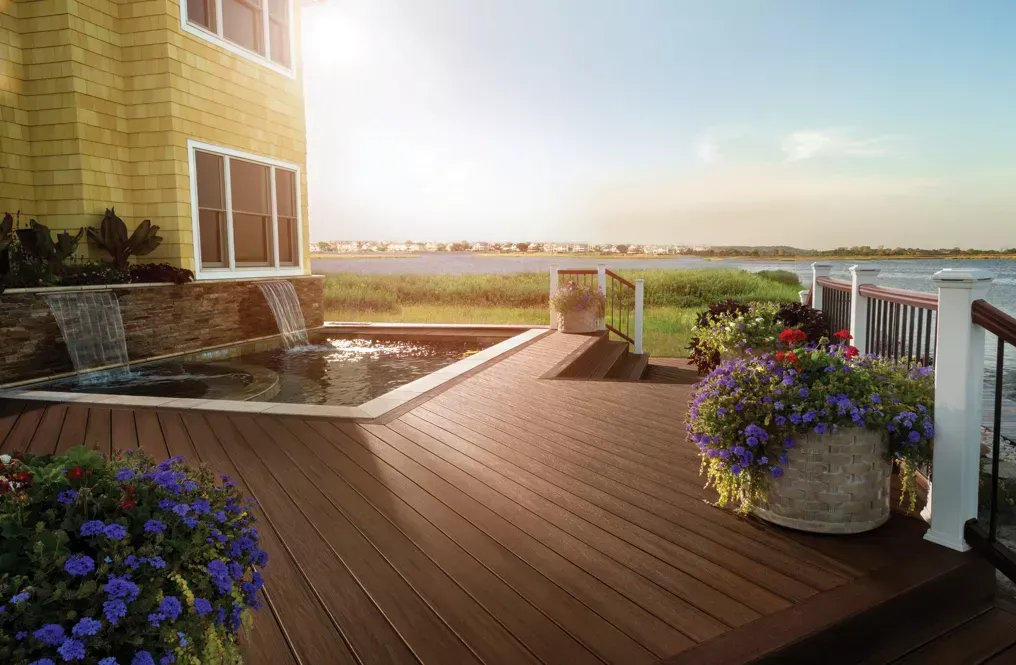 A Wooden Deck with Flowers and A Waterfall Next to A House — Bootle Timber QLD Pty Ltd in Mackay, QLD