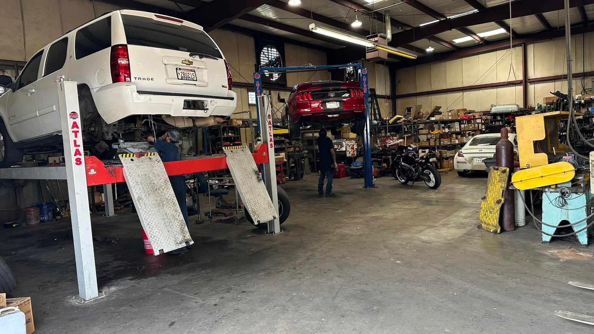 A white suv is on a lift in a garage.