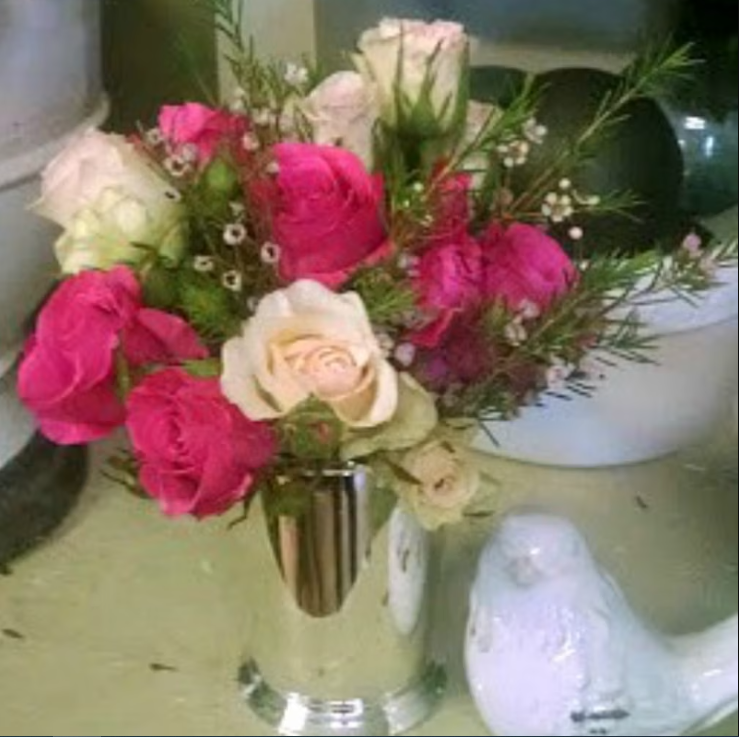 Bouquet of pink and white roses in a vase, next to a white ceramic bird.