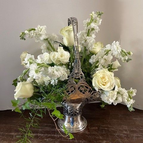 Silver flower basket filled with white roses and blossoms.