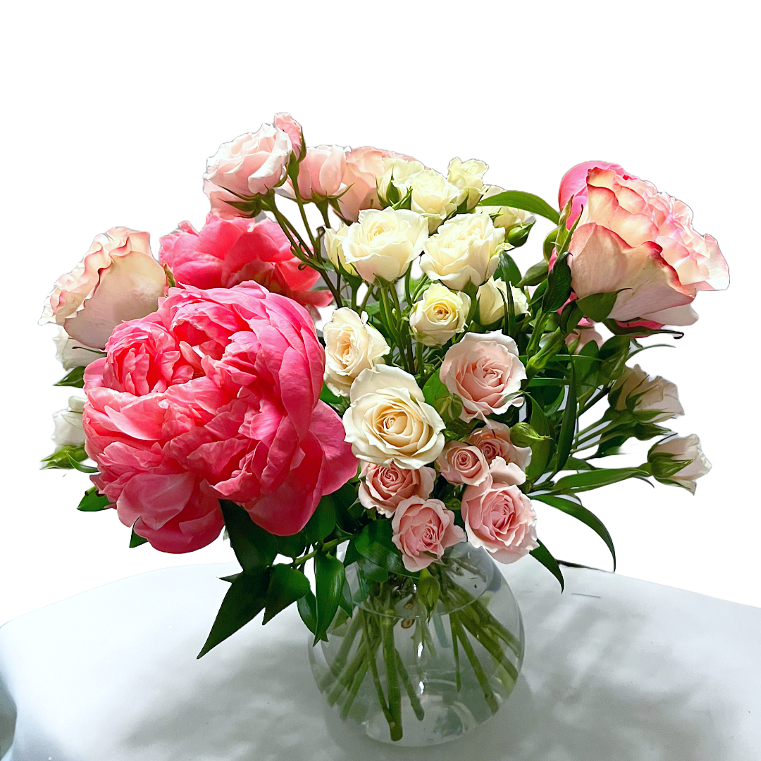 Bouquet of pink and white peonies and roses in a glass vase.