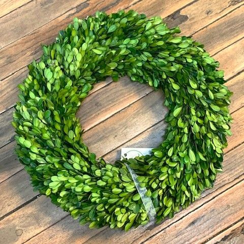 Green boxwood wreath on wooden planks.
