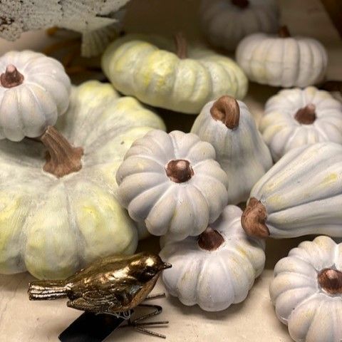 A bunch of white pumpkins are sitting on a table next to a bird.