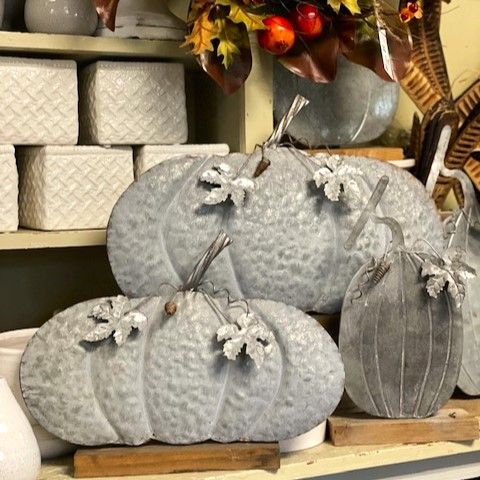A bunch of gray metal pumpkins are sitting on a table