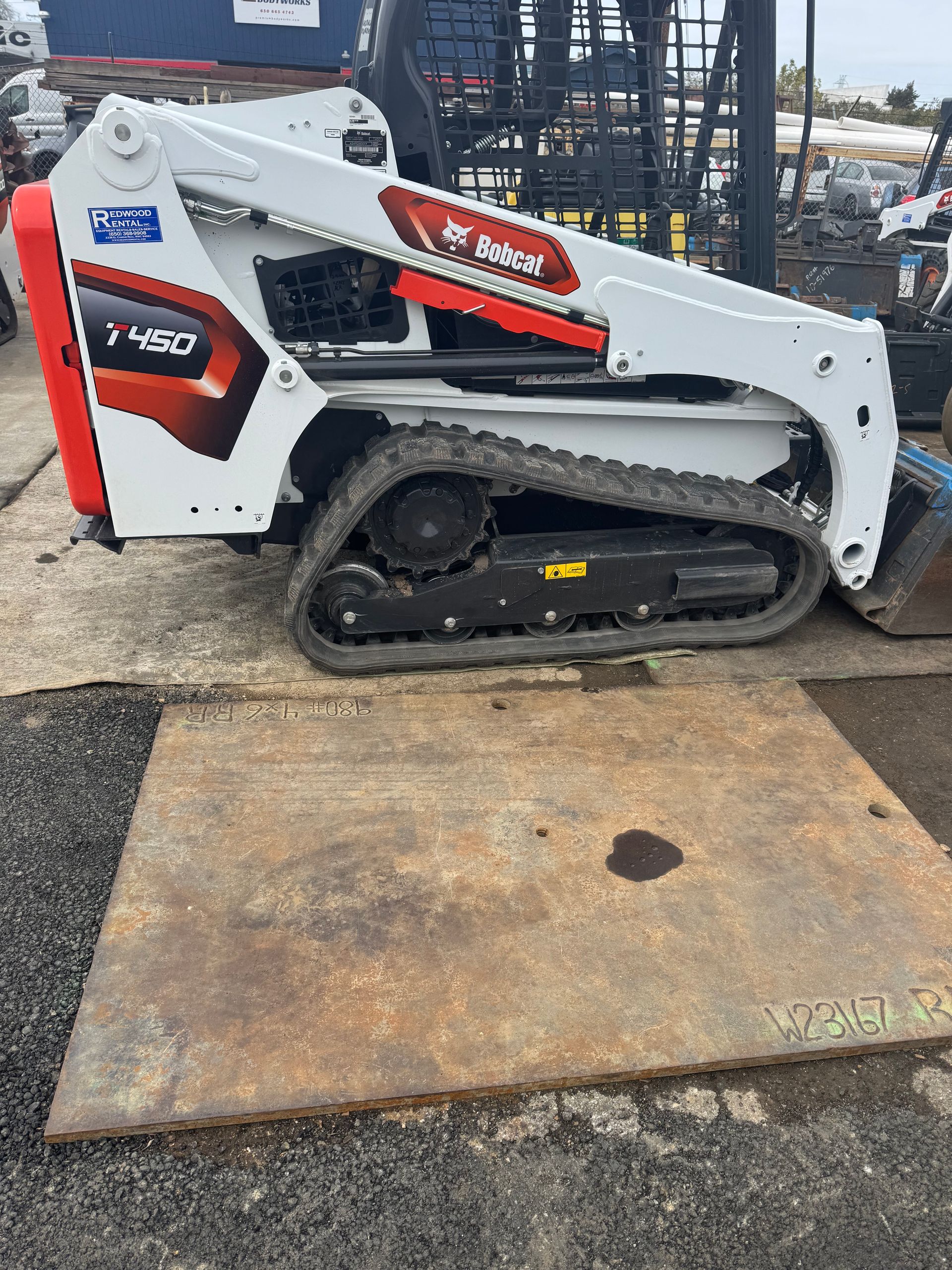 A yellow john deere skid steer is parked in a grassy field
