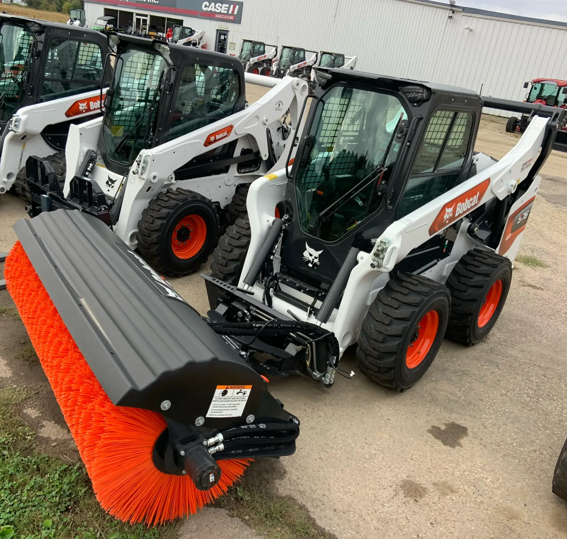 An orange bucket is sitting on the grass next to a tractor.