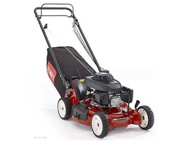 A lawn mower is cutting a lush green lawn in a backyard.