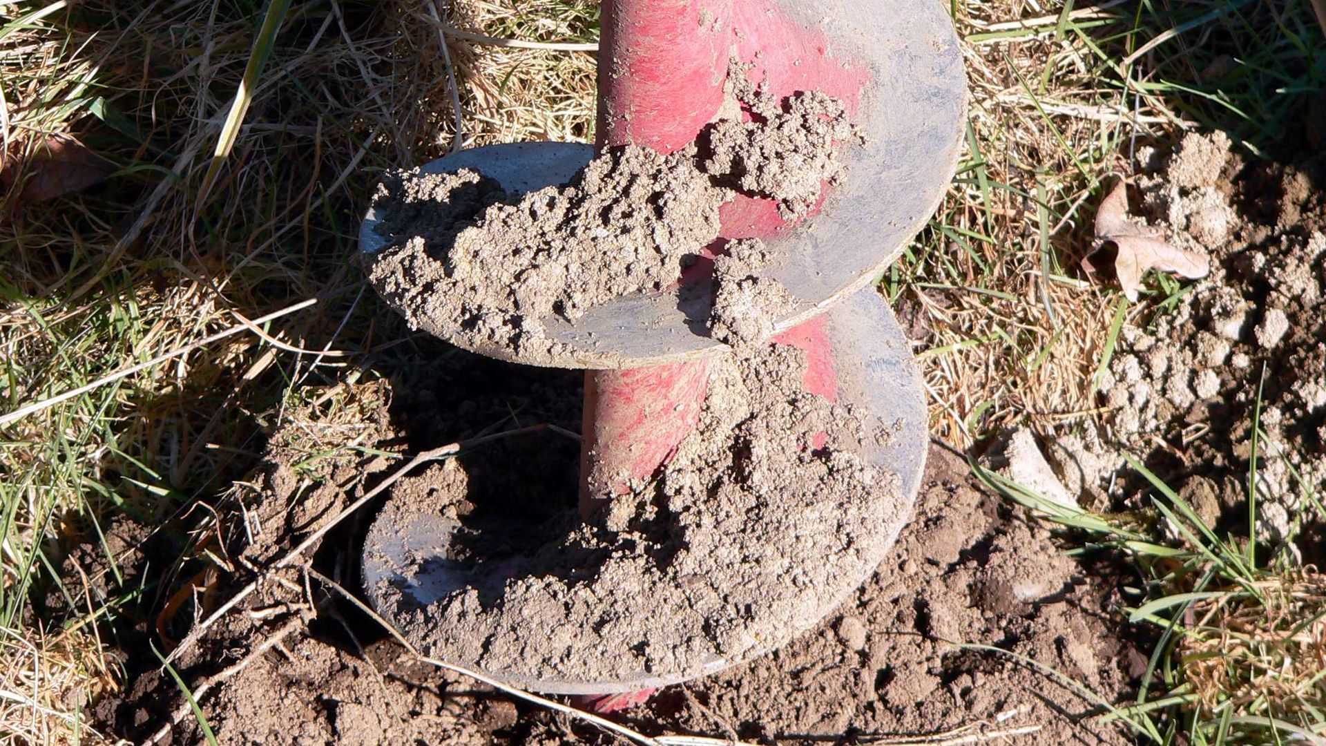 A close up of a drill bit in the dirt.