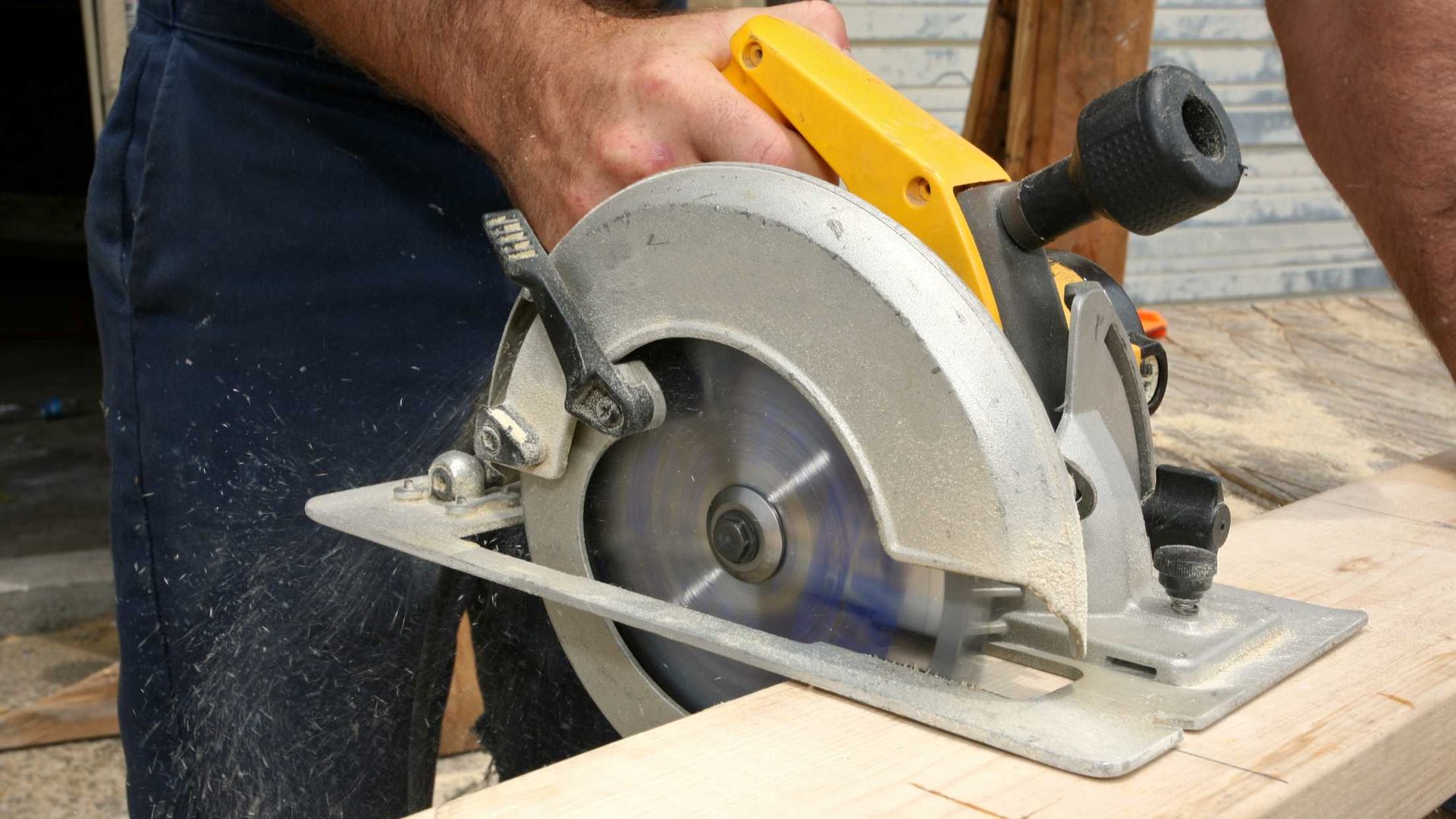 A man is using a circular saw to cut a piece of wood