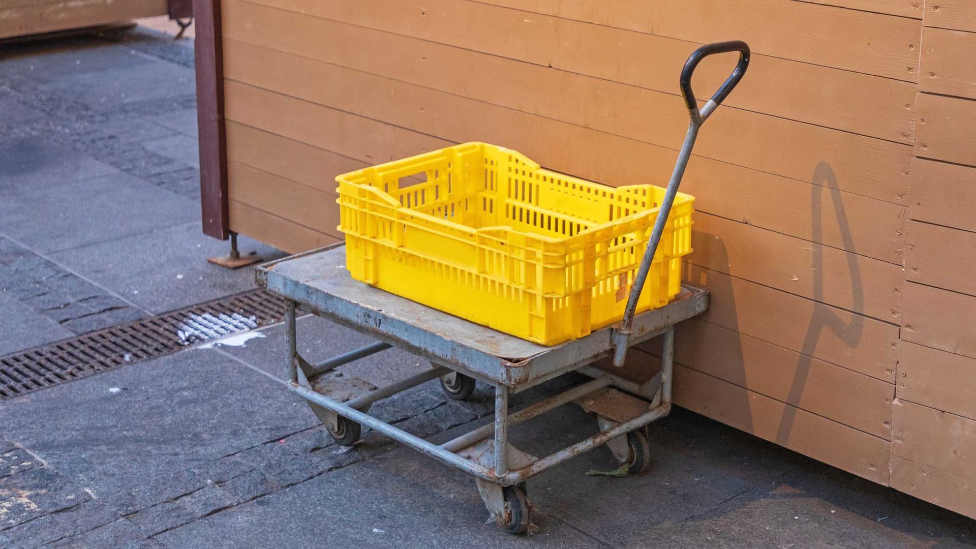 A yellow crate is sitting on top of a metal cart.