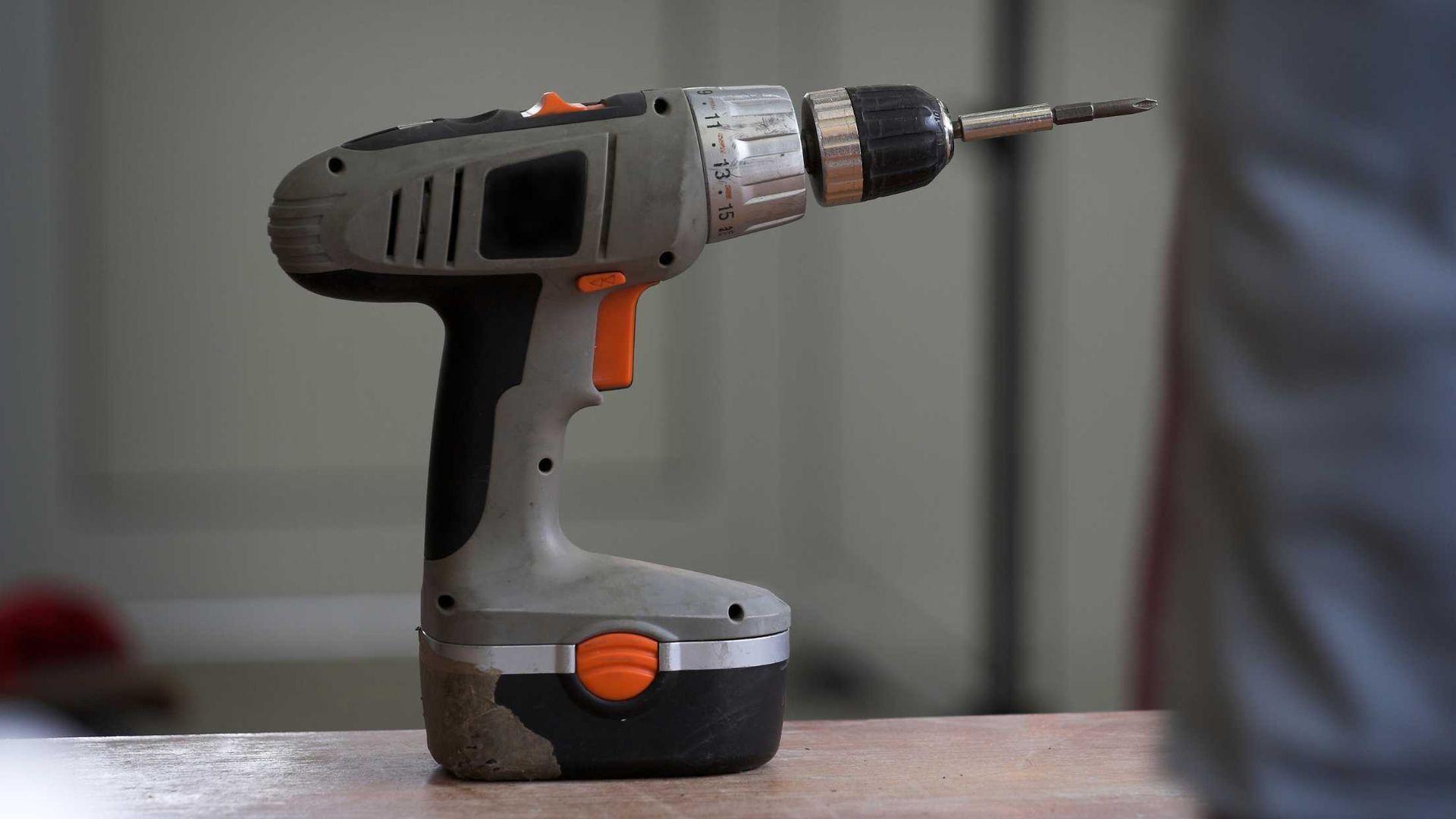 A cordless drill is sitting on a wooden table.