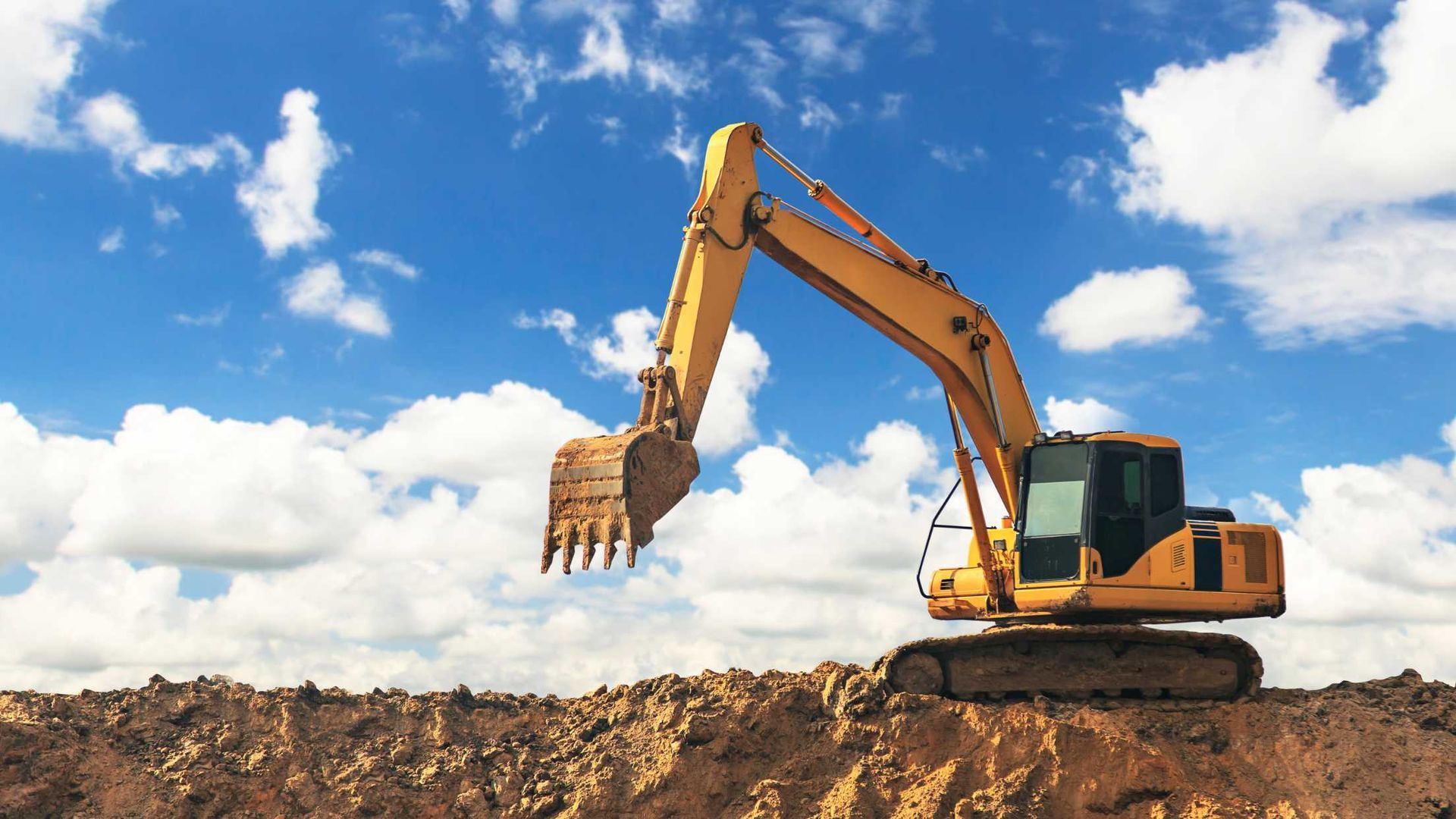 A yellow excavator is digging a hole in the dirt.