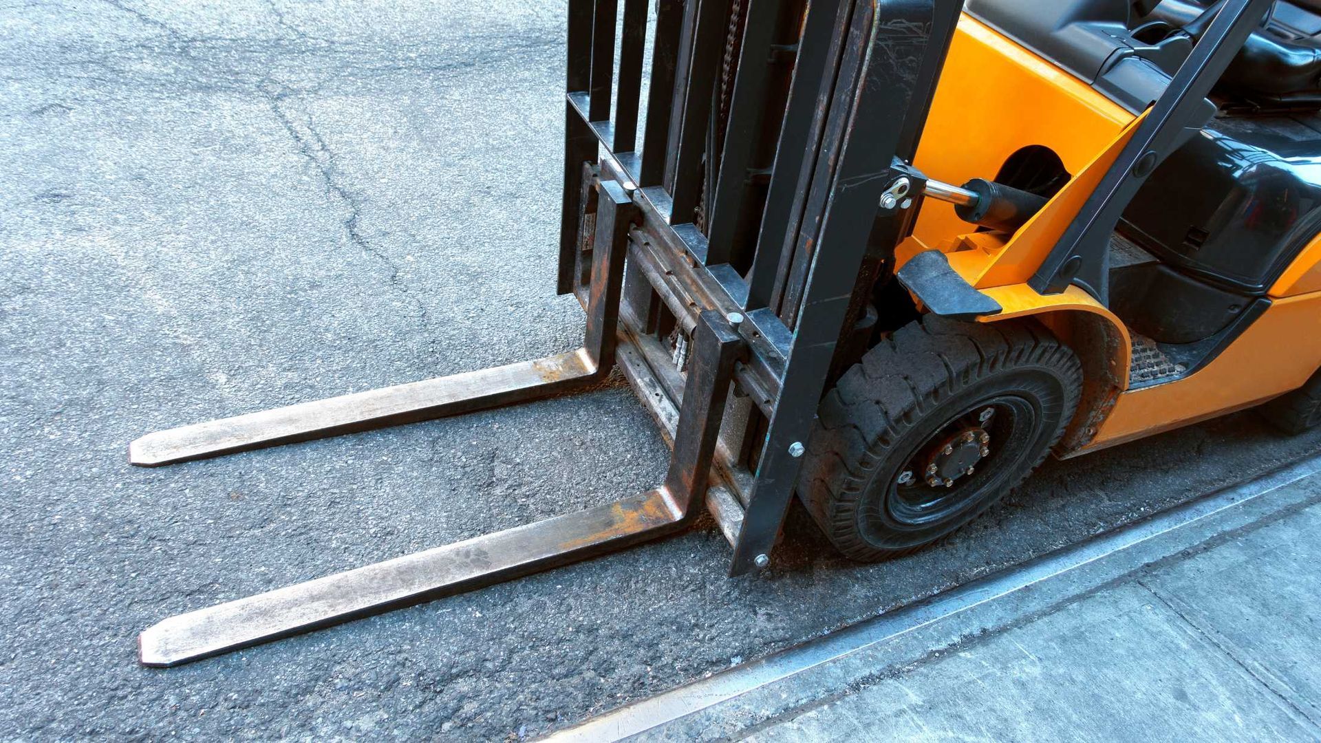 A yellow forklift is parked on the side of the road.